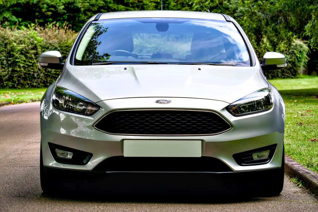 A front-facing silver Ford Focus parked on a tree-lined road, showcasing sleek design and style.