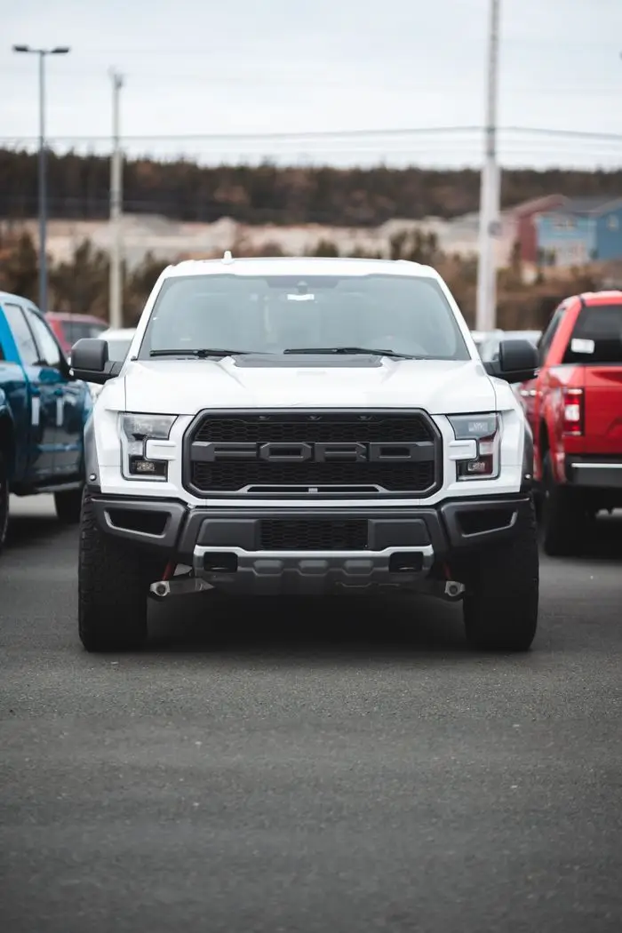 White truck parked outdoors with other vehicles in a lot.
